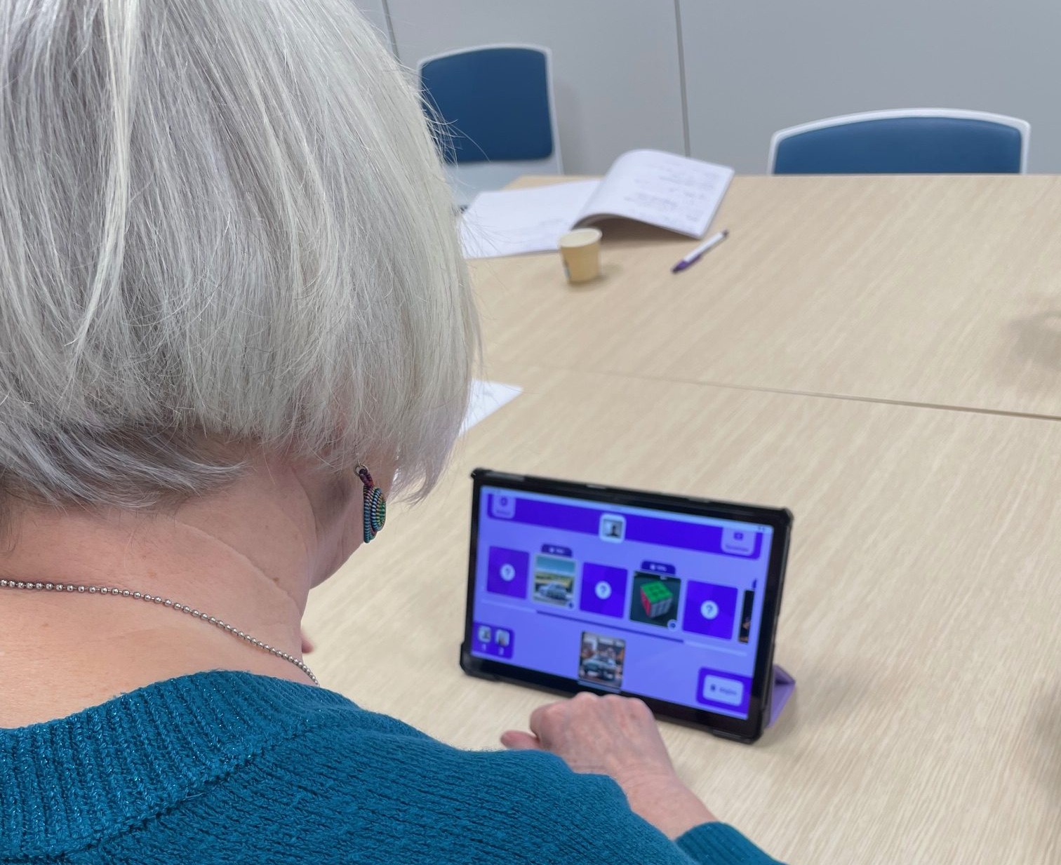 Senior qui joue à un jeu avec Gena-App sur une tablette numérique