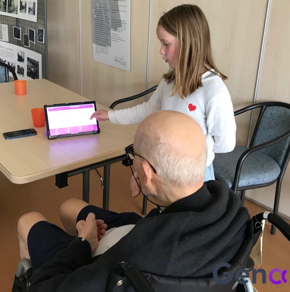 Une fillette et un senior jouent sur une tablette numérique à l'application Gena
