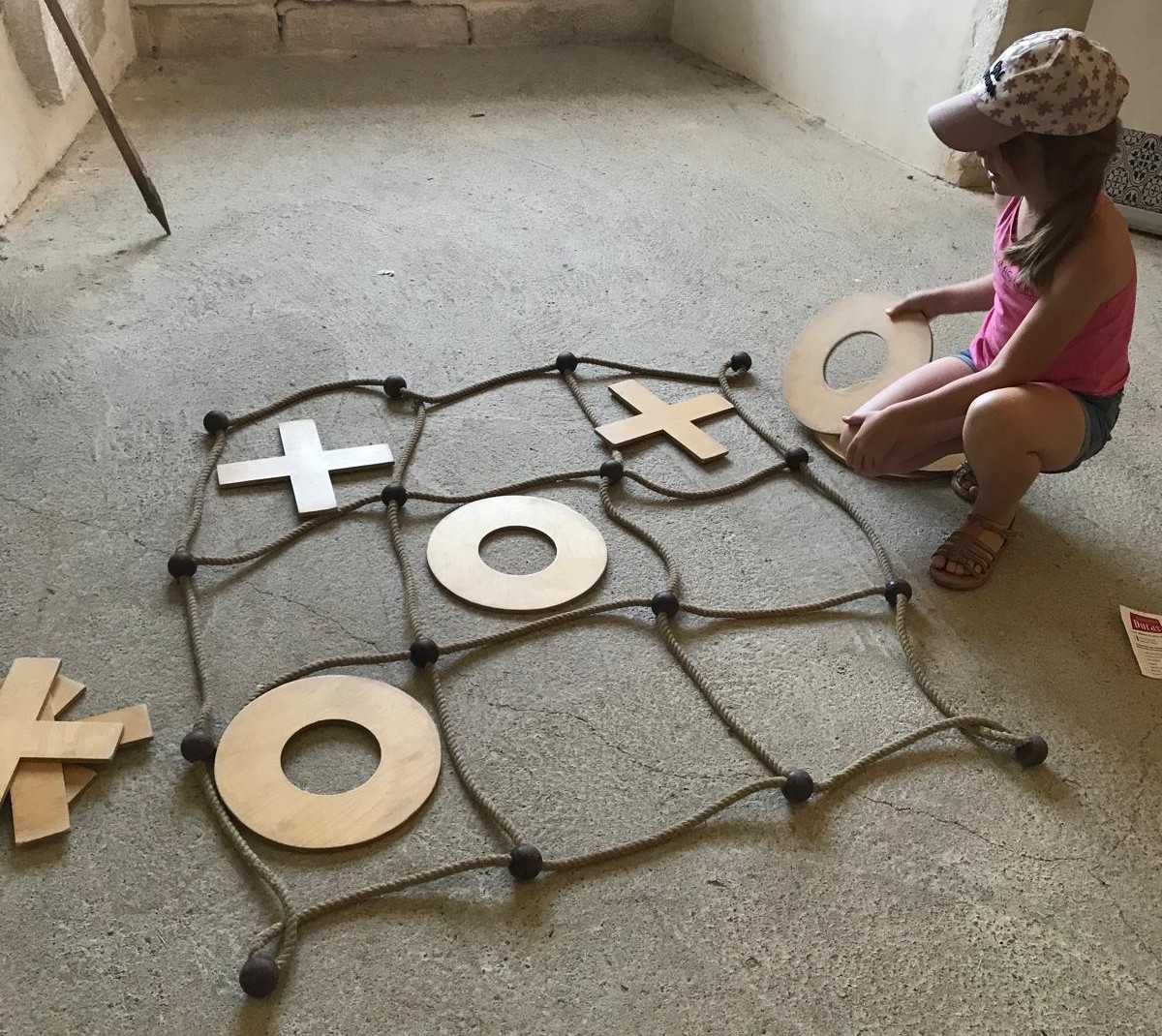 Une petite fille joue au morpion avec des cordes marines et de larges pièces en métal